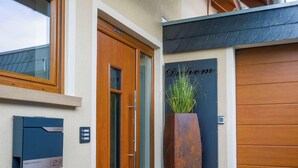 Une entrée d’immeuble avec une porte en bois, une enseigne indiquant « Dachheim » et une boîte aux lettres portant le numéro « 23 ».
