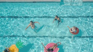 Ein Schwimmbecken mit klarem Wasser, Bahnen und aufblasbaren Spielzeugen.