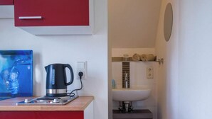 Eine Küchenzeile mit Kaffeemaschine, Spüle und Spiegel.