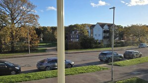 Une rue résidentielle bordée de voitures garées, avec des maisons en arrière-plan.