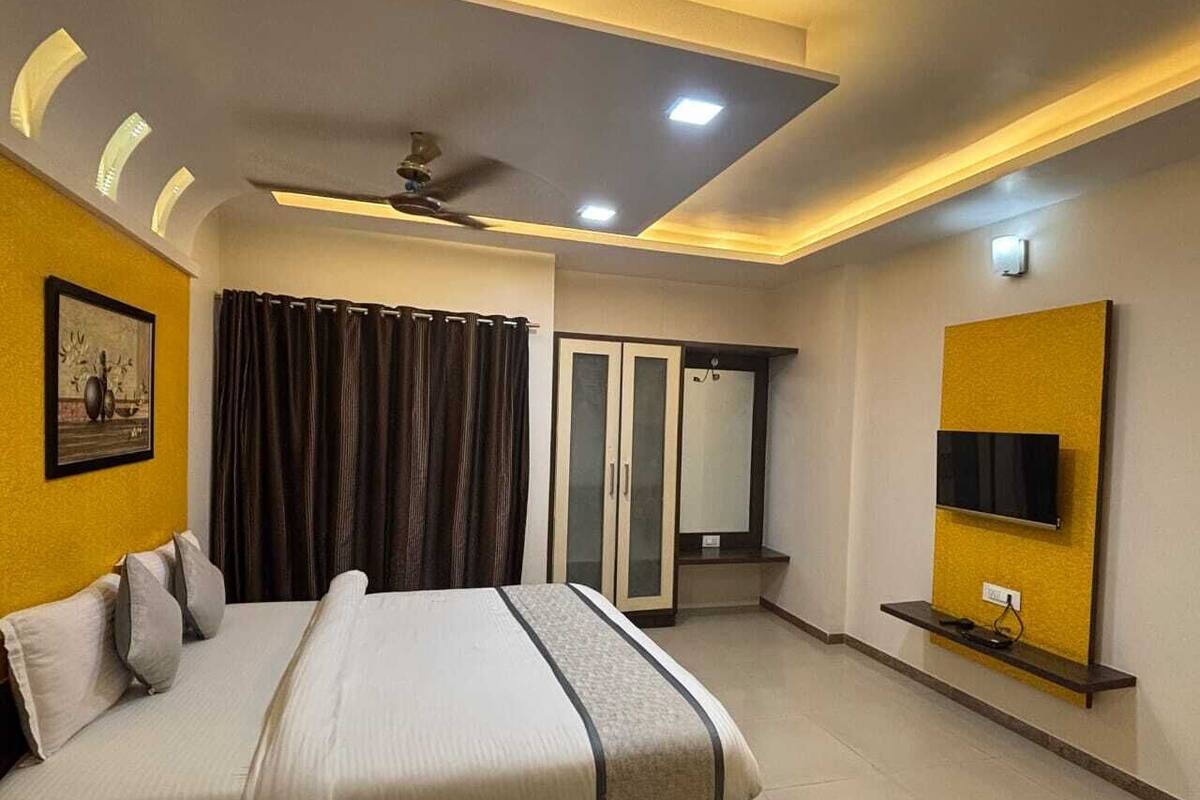 A modern hotel room with a bed, a television, a wardrobe, and a ceiling fan.