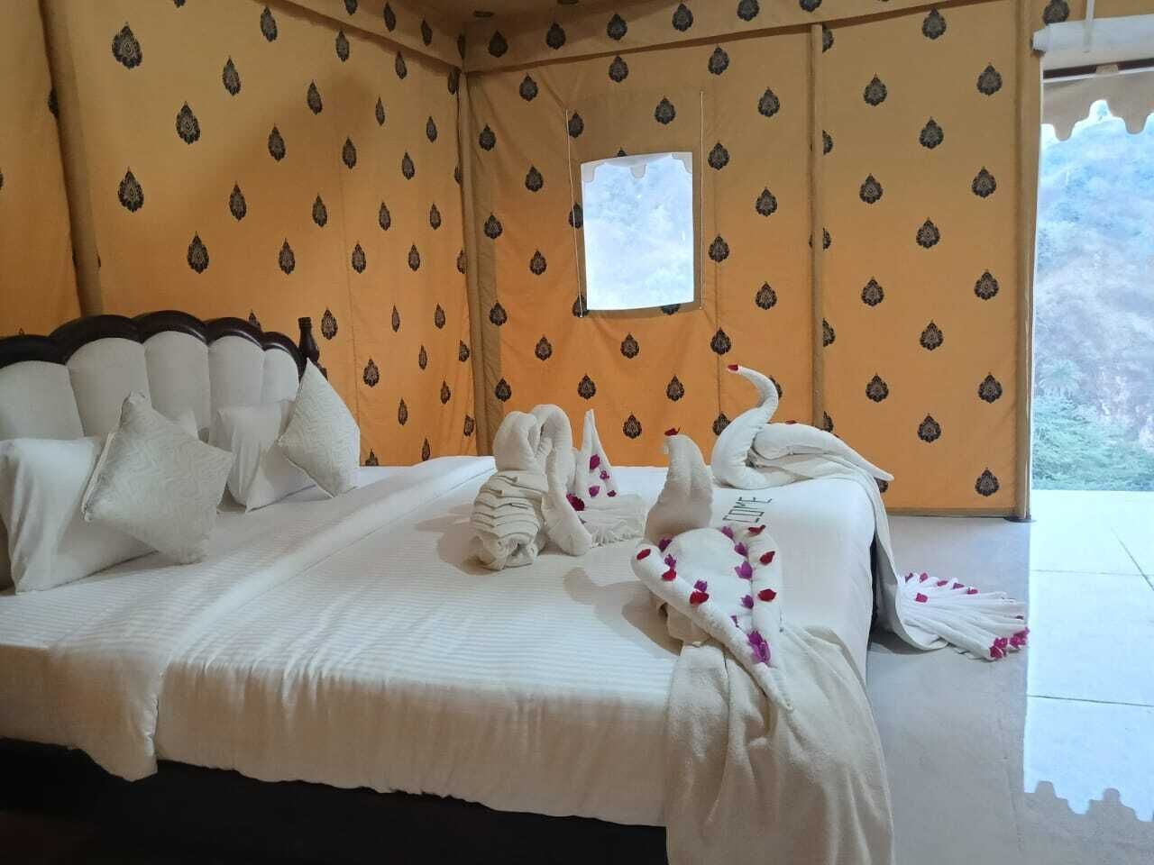 A bed with white bedding and pillows, a window, and a patterned wall.