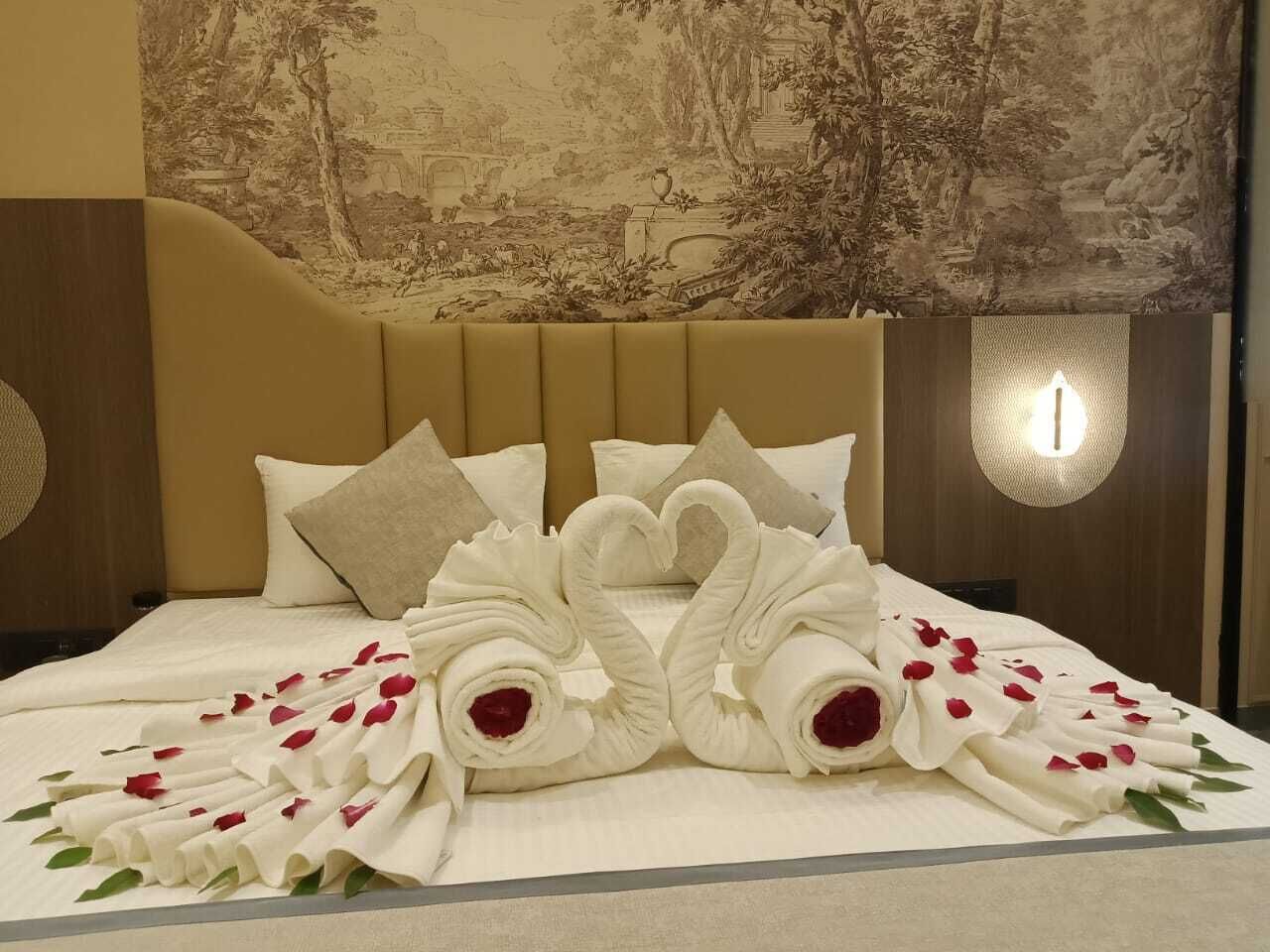 A hotel room with a bed featuring a decorative arrangement of towels and rose petals.