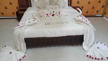 A bed with a 'WELCOME' sign, swan-shaped pillows, and a 'WEL-COME' sign on the bedspread.