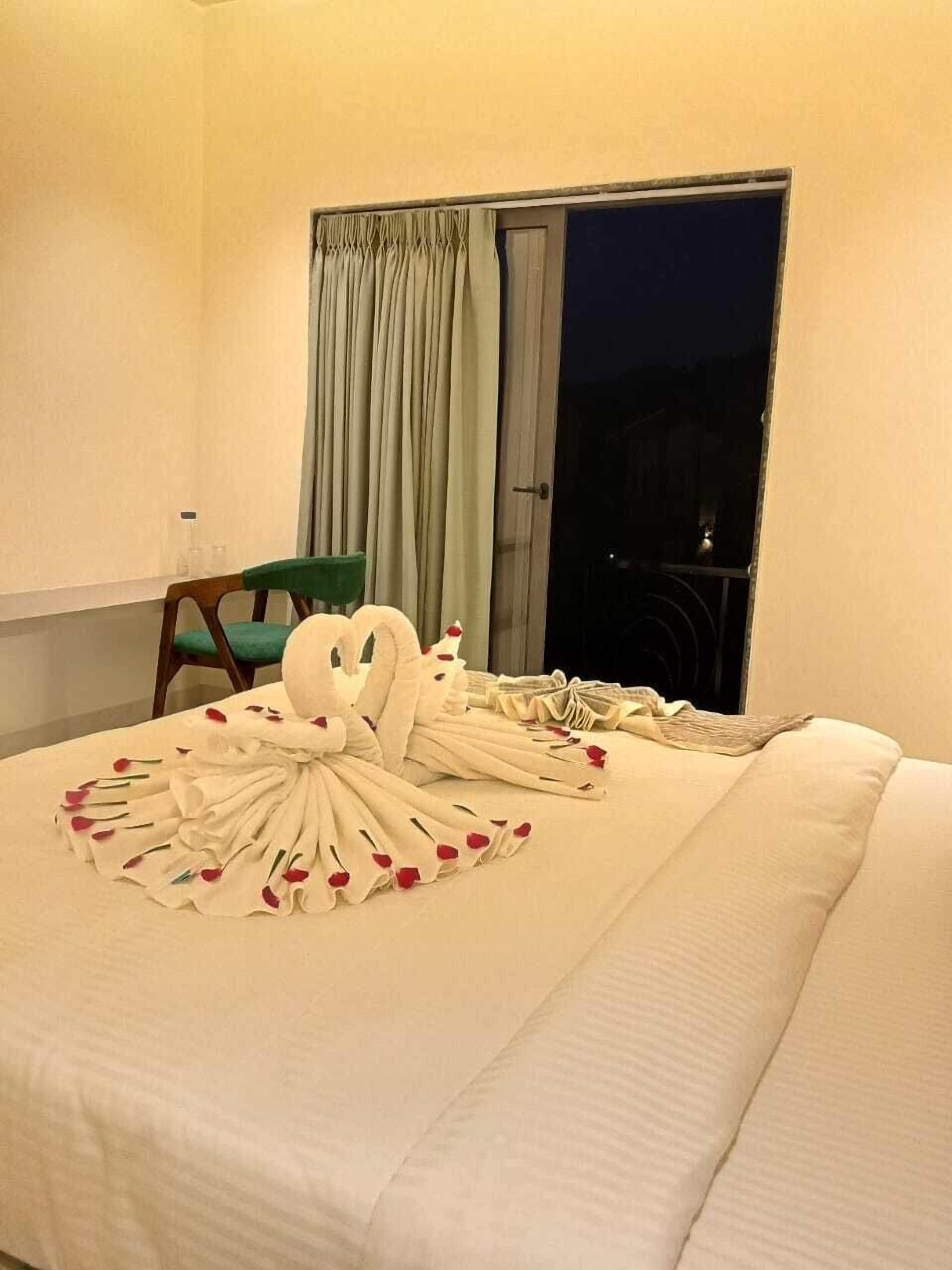 A hotel room with a bed, a chair, and a window with curtains.