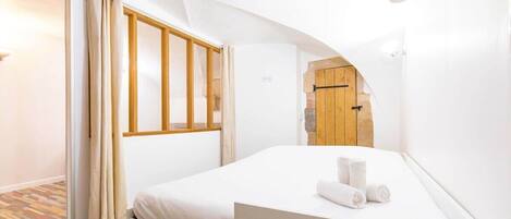 Ein Schlafzimmer mit einem Bett, einer Holztür und einer weißen Wand.