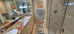 A bathroom with a marble vanity, two sinks, a glass shower enclosure, and decorative towels. - Eden E 205 Gulf Front Condo with Stunning Views! (Pensacola)