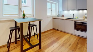 Una cucina moderna con pavimento in legno, un tavolo da pranzo con sgabelli e un forno integrato.
