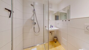 Un bagno moderno con doccia vetrata, lavandino e specchio.
