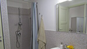 A bathroom with a shower, a sink, and a mirror. - The Blue Room Courtyard (Scicli)