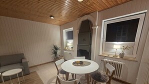 A cozy dining area with a round table, four chairs, a small side table, a sofa, and a window with a view.