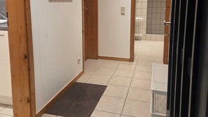 A hallway with wooden doors, a tiled floor, and a small rug.