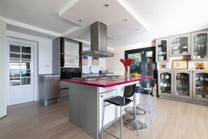 Una cocina moderna con una isla central, taburetes de bar, microondas y una campana extractora de acero inoxidable.