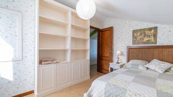 Un dormitorio con cama, armario, mesita de noche, lámpara y un cuadro en la pared.