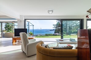 Un salon moderne doté d’une grande fenêtre, d’un téléviseur à écran plat, d’un canapé et d’une table basse.