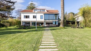 A modern two-story house with a well-maintained lawn, a stone pathway leading to the entrance, and a large glass window on the second floor.