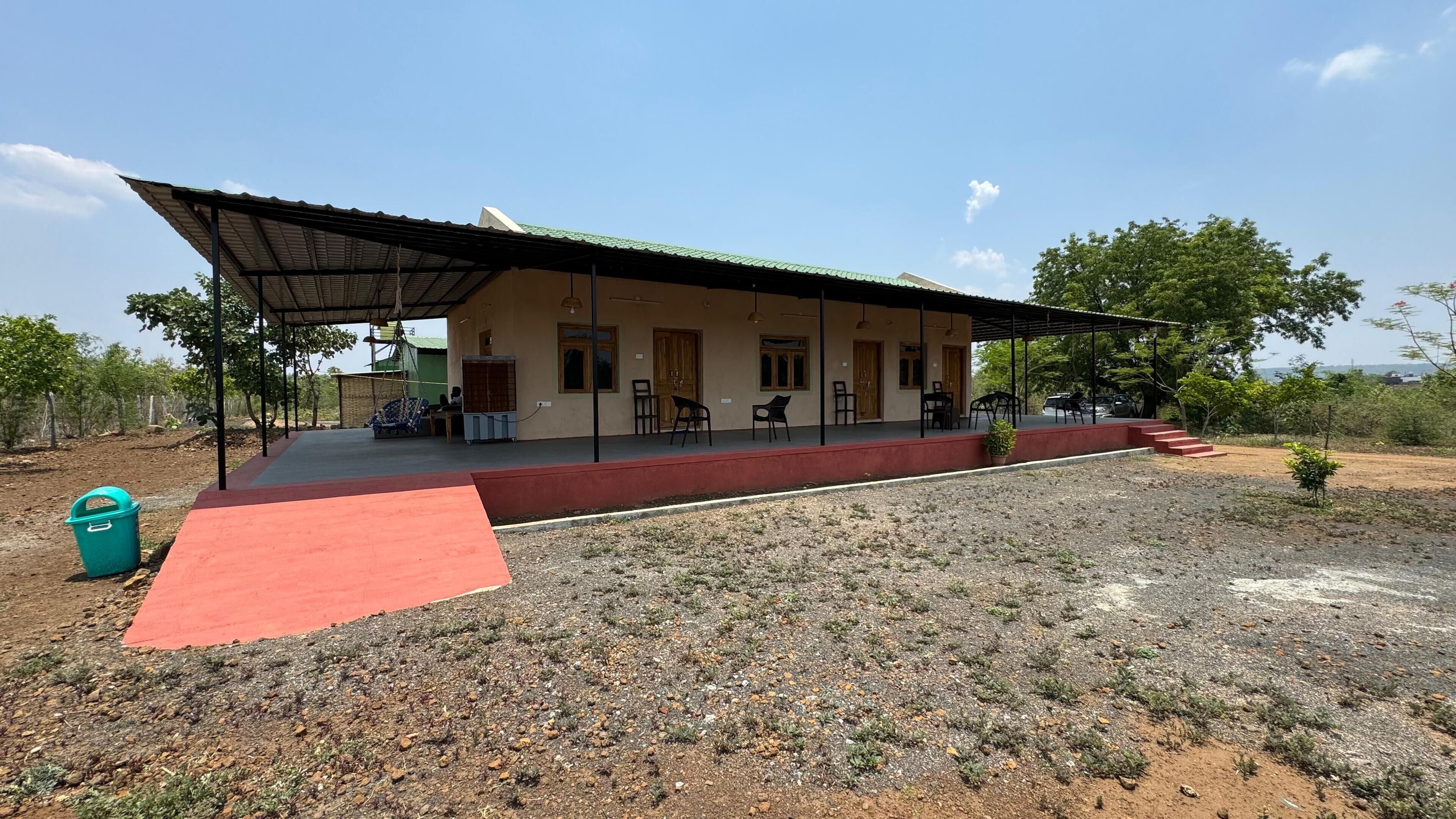 A building with a covered porch, outdoor seating, and a red carpet leading to the entrance.