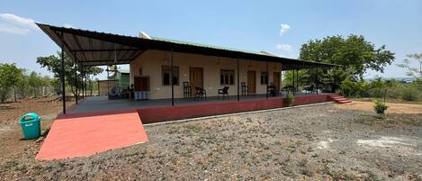 A building with a covered porch, outdoor seating, and a red carpet leading to the entrance.