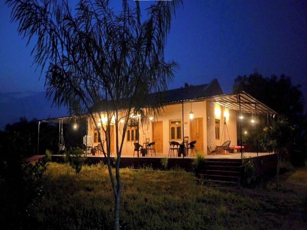 A two-story house with a covered patio, outdoor seating, and a well-lit entrance.