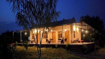 Una casa de dos pisos con un porche cubierto, mobiliario exterior y una entrada bien iluminada.