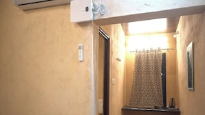 Ein schmaler Flur mit einem Badezimmer, das einen waschbärgemusterten Duschvorhang, ein kleines Waschbecken und einen Spiegel zeigt.