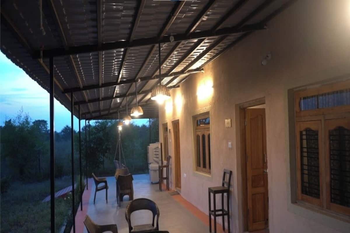 Un espace extérieur abrité, aménagé avec des chaises et doté d’un luminaire suspendu.