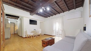 Een woonkamer met een bank, een salontafel en een eethoek met een tafel en stoelen.