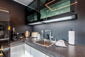 A modern kitchen with a stainless steel sink, a coffee maker, a toaster, and a hanging towel. - Fanderhüs in Westerland (Sylt)