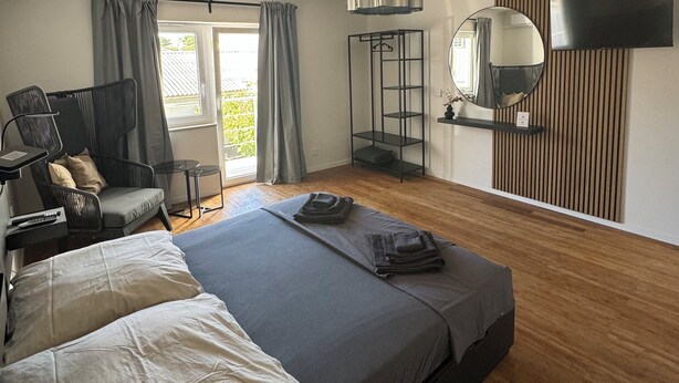 A modern bedroom with a bed, a chair, a TV, and a large window. - Two-bedroom House Lara Denona (Novalja)