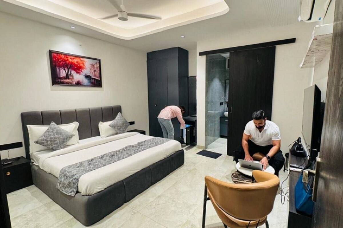 A modern bedroom with a large bed, a desk, and a chair.