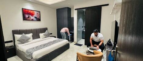 A modern bedroom with a large bed, a desk, and a chair.