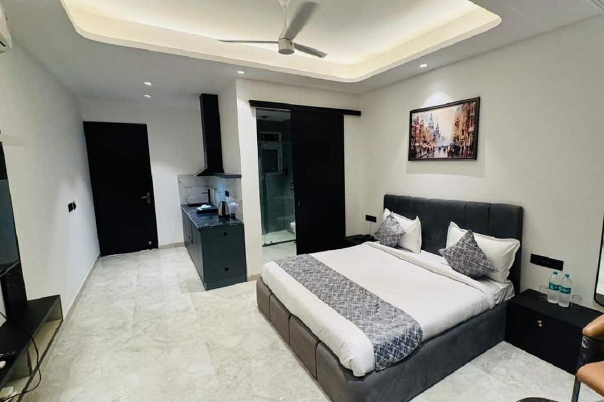 A modern hotel room with a large bed, a desk, and a seating area.