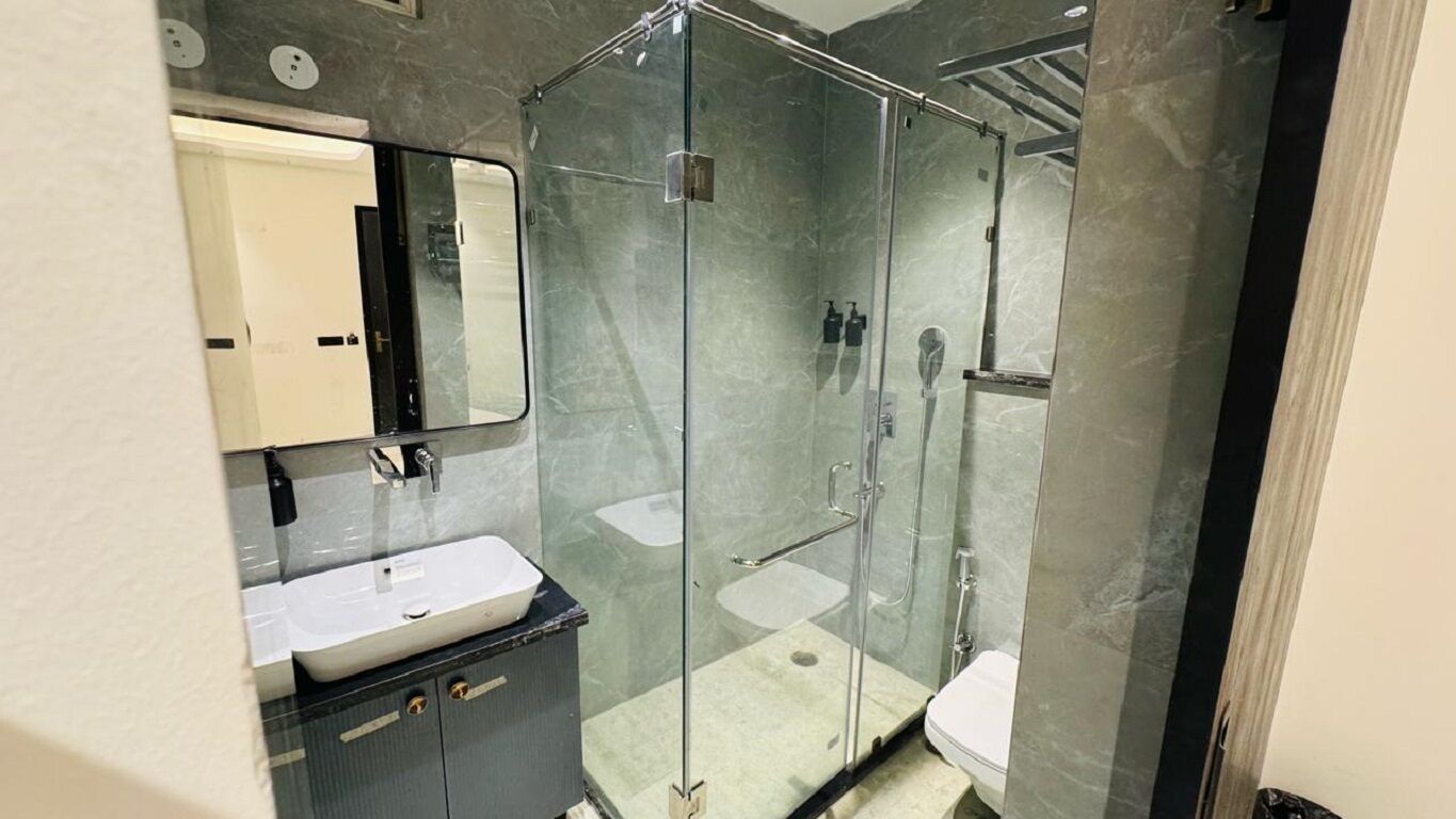 A modern bathroom with a glass-enclosed shower, a white sink, and a dark vanity.