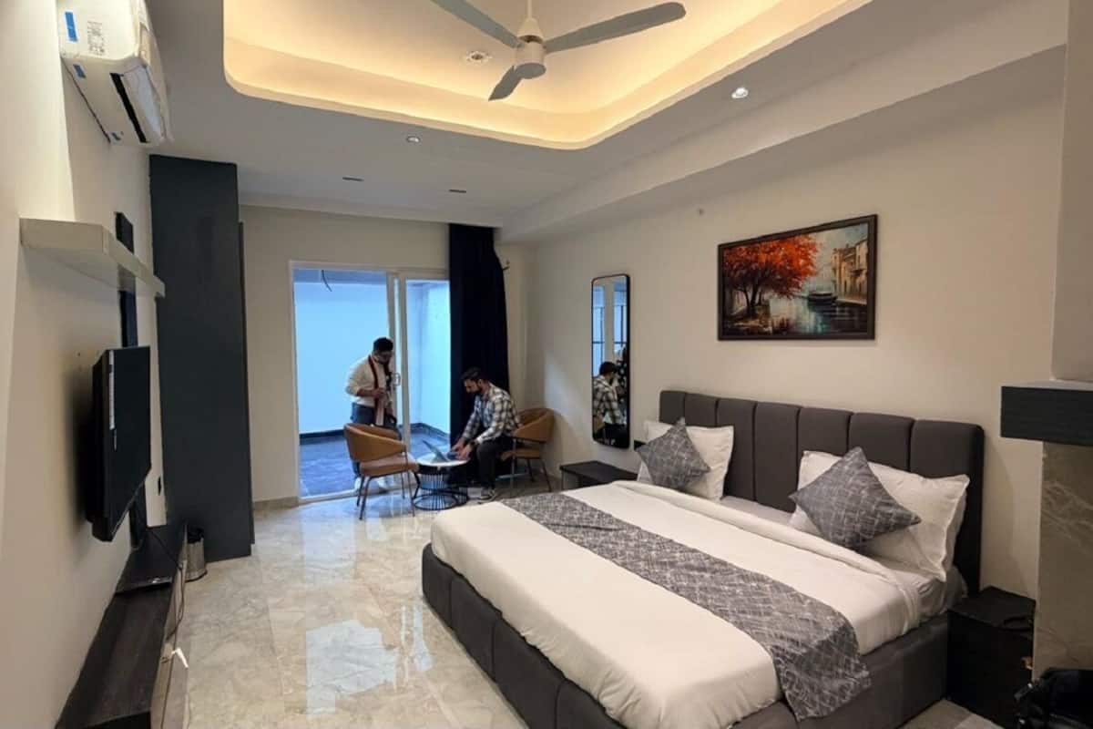 A modern bedroom with a large bed, a ceiling fan, and a painting on the wall.
