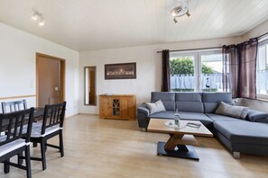 A living room with a grey sofa, wooden dining table, chairs, and a cabinet. - Apartment No. 1 with Terrace (Attendorn)
