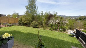 A well-maintained garden with a lawn, a wooden fence, and various trees.