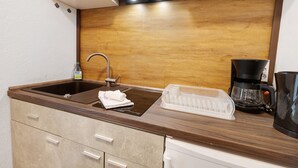 A kitchenette with a sink, a coffee maker, and a dish rack.