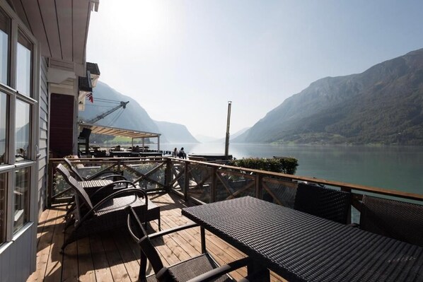 A wooden deck with outdoor seating, overlooking a lake and mountains. - Skjolden Resort (Skjolden)