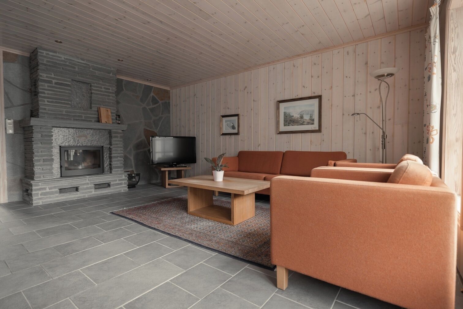 A living room with a stone fireplace, a television, a sofa, and a coffee table.