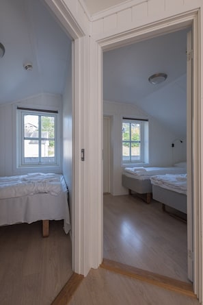 A room with two beds, wooden flooring, and a window with a view of greenery. - Skjolden Resort (Skjolden)
