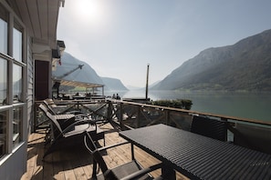 A wooden deck with outdoor seating overlooking a lake and mountains. - Skjolden Resort (Skjolden)