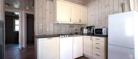 A kitchen with white cabinets, a white refrigerator, and a microwave.