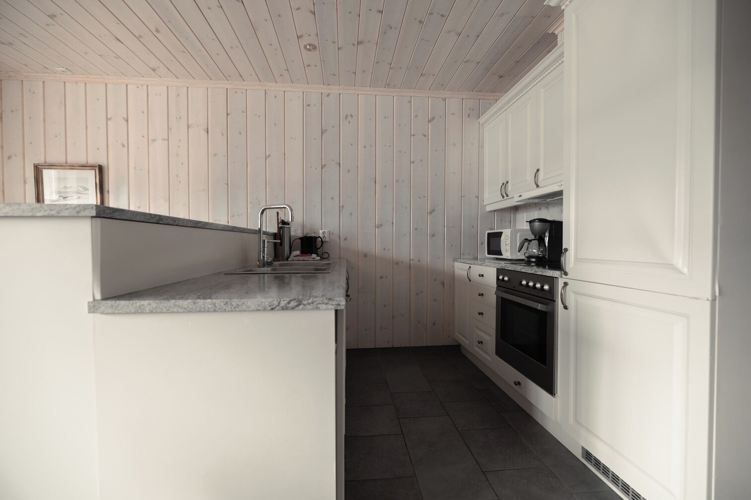 Une cuisine de taille réduite, équipée d’un évier, d’une cuisinière, d’un four à micro-ondes et de placards.