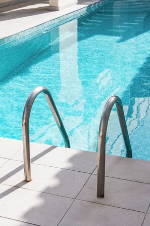 A swimming pool with metal handrails and tiled flooring. - Primula e Foca (St. Julian's)