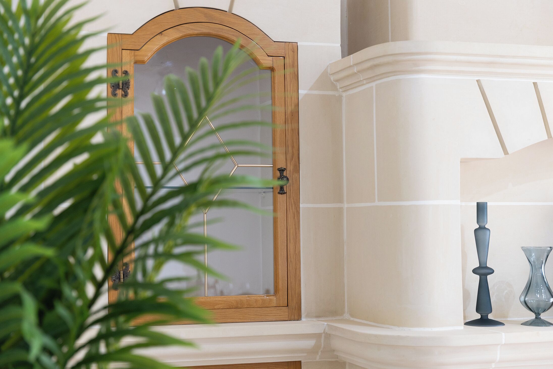 Esquina de una habitación con un espejo de madera, una pared blanca y una planta en maceta.