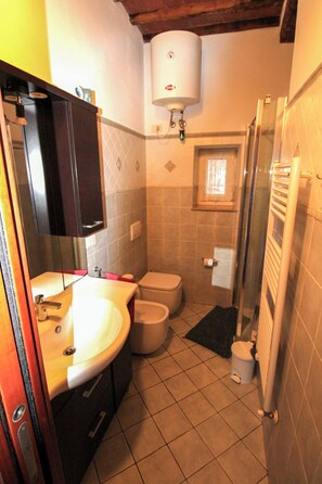 A small bathroom with a toilet, sink, and shower. - Casa Carlo (Rio Marina)
