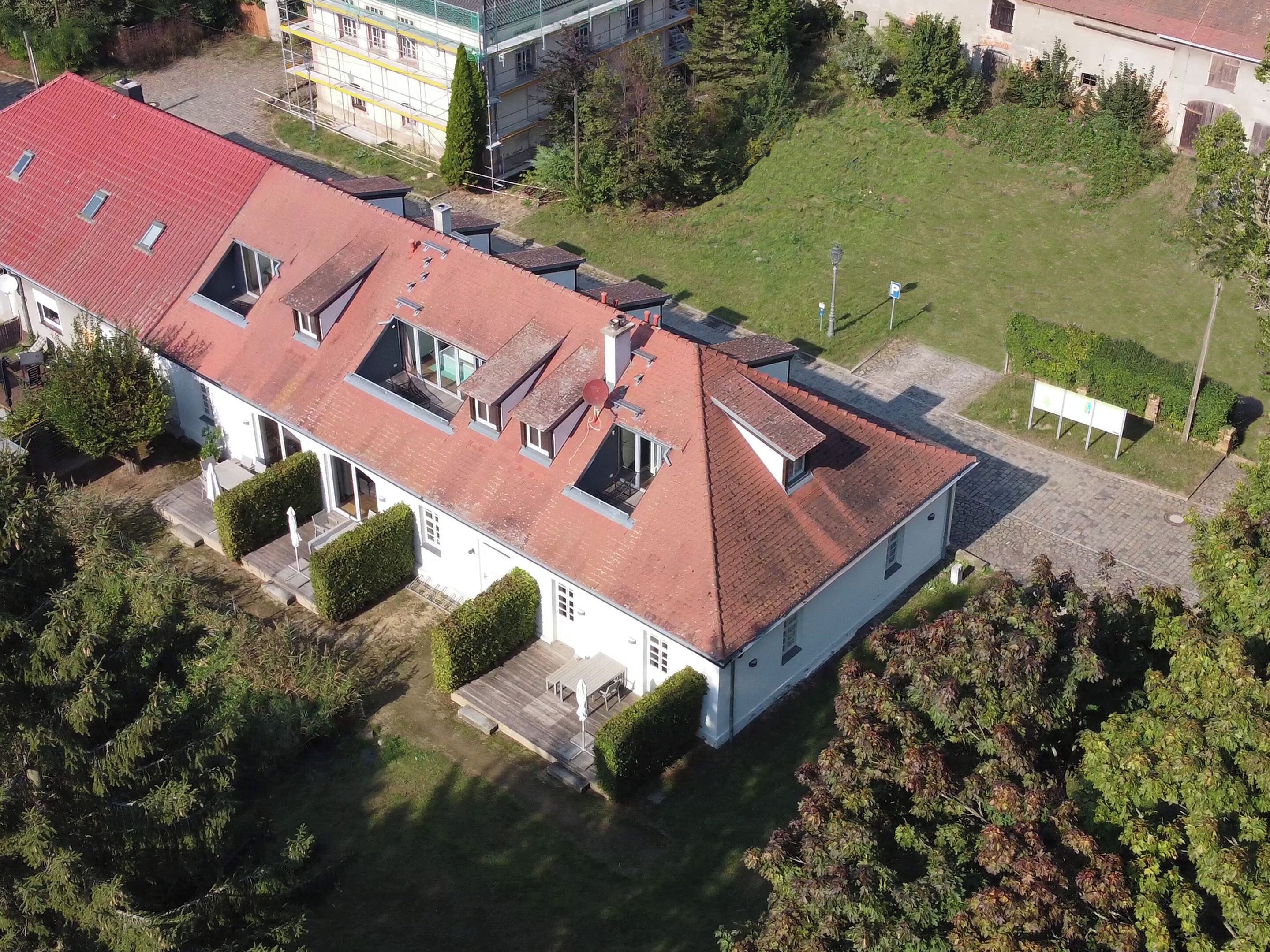 A two-story building with a red-tiled roof, multiple skylights, and a well-maintained lawn.