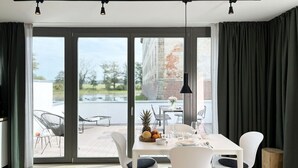 A modern dining area with a white table set for four, large windows, and a view of the outdoors. - Resort Schloss Reinharz (Bad Schmiedeberg)