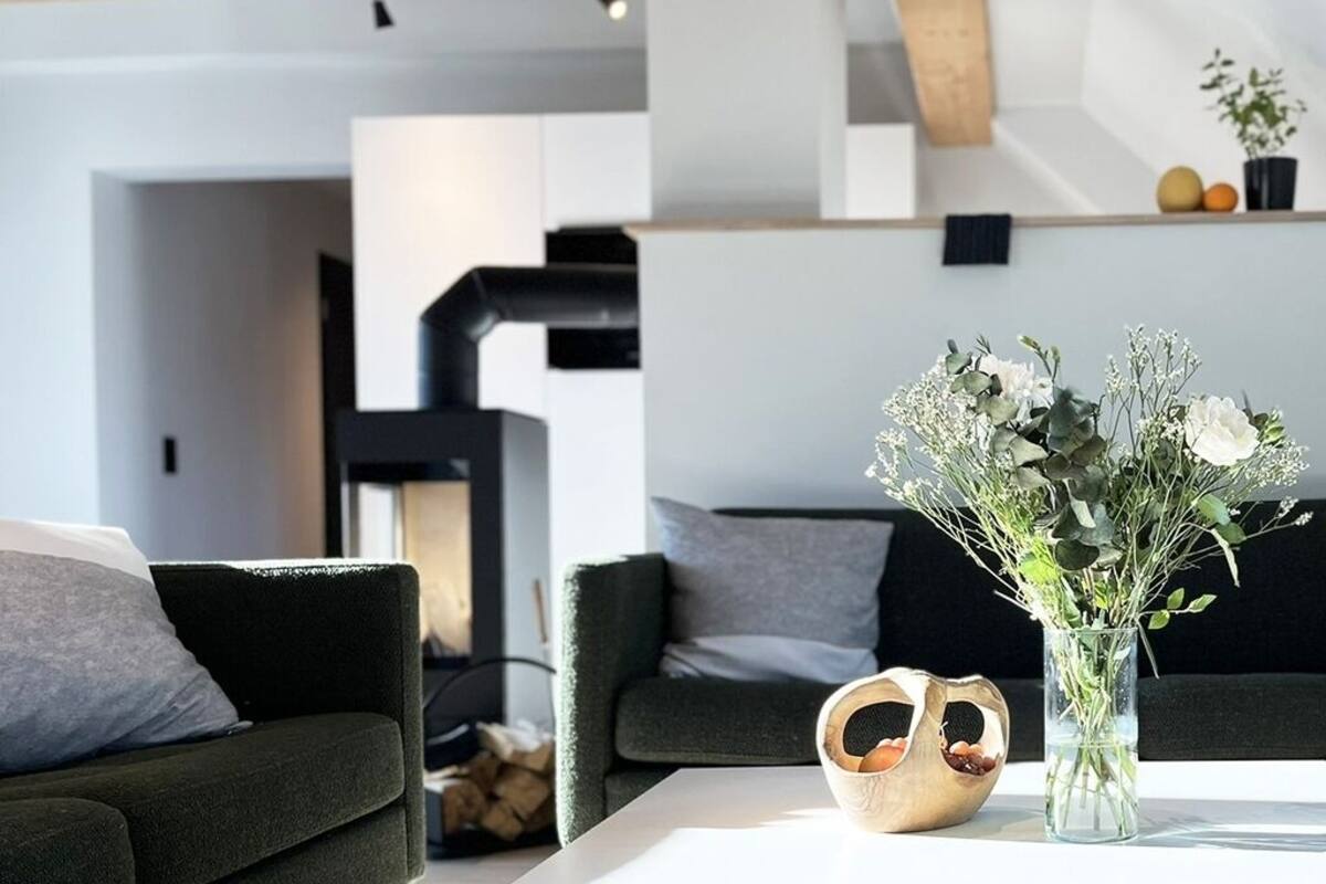 A modern living room with a sofa, a coffee table, and a vase with flowers.