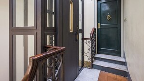 A staircase leading to a dark green door with a brass knocker, a wooden handrail, and a metal gate. - NAVONA PENTHOUSE APARTMENT WITH TERRACES (Roma)